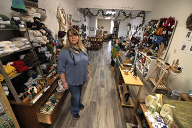 Woman standing in a craft store with shelves of yarn and supplies