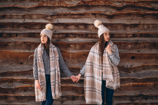 Two women holding hands against a wooden wall